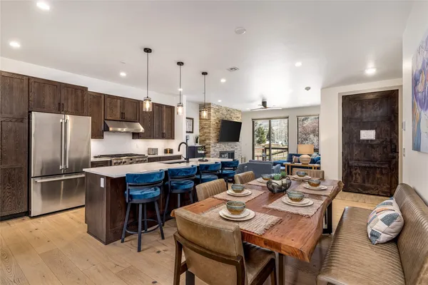 a kitchen with stainless steel appliances granite countertop a kitchen island hardwood floor sink stove dining table and chairs