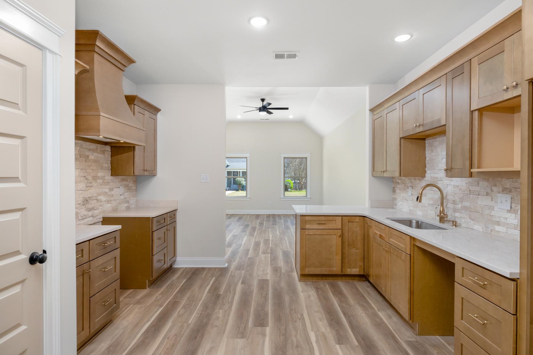 319 North Maple Street Covington, TN 38019 - Photo 15 of 32 Kitchen featuring backsplash, light stone counters, light wood-style floors, recessed lighting, and a peninsula
