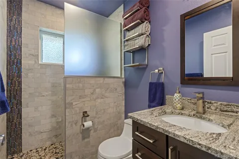 a bathroom with a granite countertop toilet sink and mirror