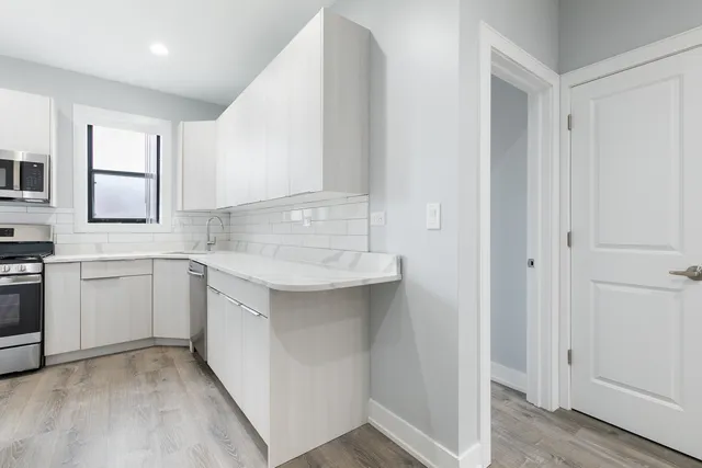 a kitchen with white cabinets and sink