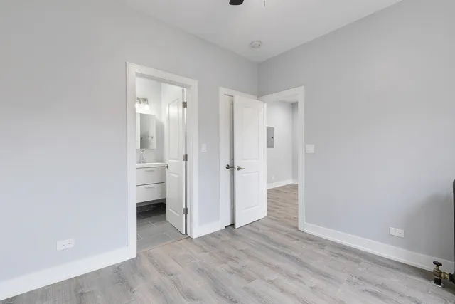 a view of an empty room with wooden floor and closet