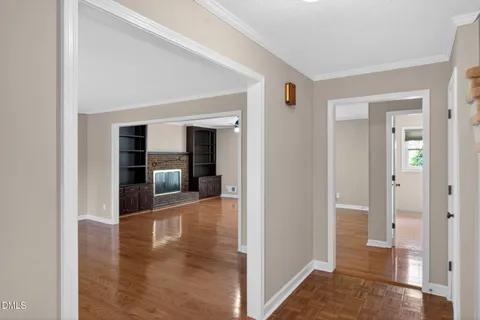 an empty room with wooden floor a fireplace and windows