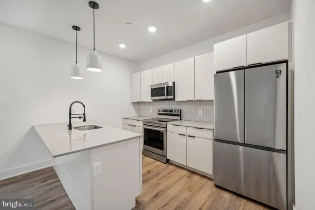 a large kitchen with kitchen island a stove a refrigerator a sink dishwasher and a oven with wooden floor