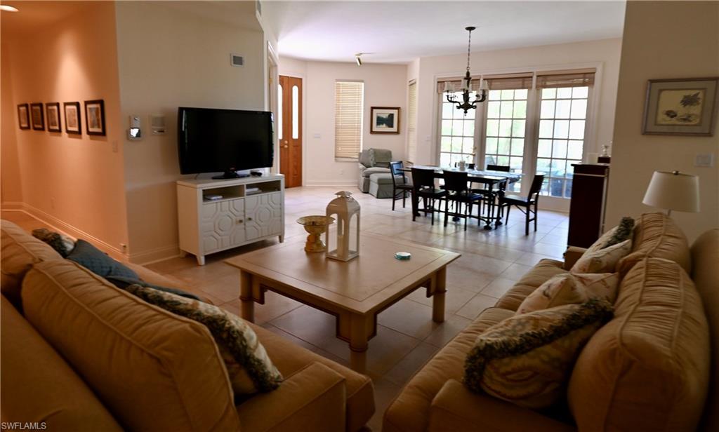 157 Colonade Circle, Unit 1002 Naples, FL 34103 - Photo 2 of 23 Tiled living room with a chandelier