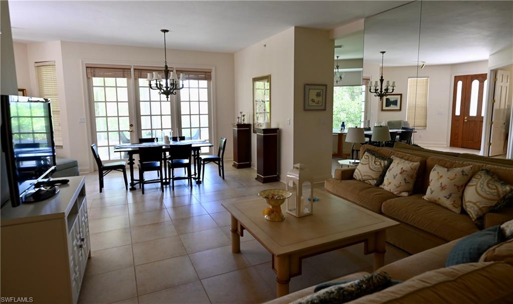 157 Colonade Circle, Unit 1002 Naples, FL 34103 - Photo 3 of 23 Tiled living room with a chandelier