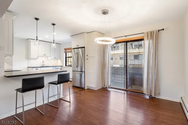 a kitchen with stainless steel appliances granite countertop a refrigerator a sink and white cabinets