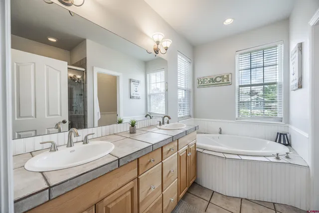 a bathroom with a sink double vanity granite tub shower and a mirror