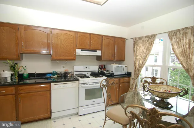 a kitchen with a stove white cabinets a table and chairs