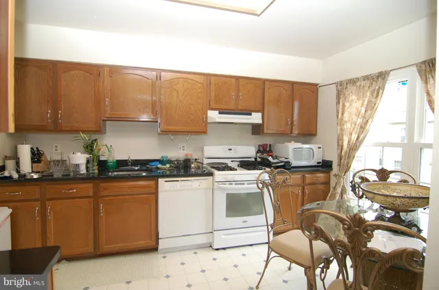 a kitchen with stainless steel appliances granite countertop a stove a sink dishwasher and white cabinets with wooden floor