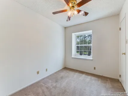 an empty room with a window and a fan