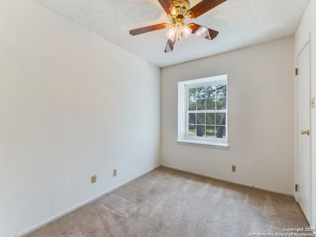 an empty room with a window and a fan