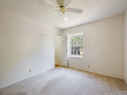an empty room with a chandelier fan and windows
