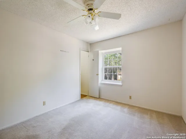 an empty room with a chandelier fan and windows