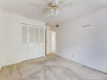 an empty room with windows and fan