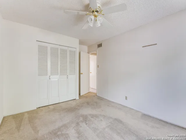 an empty room with windows and fan