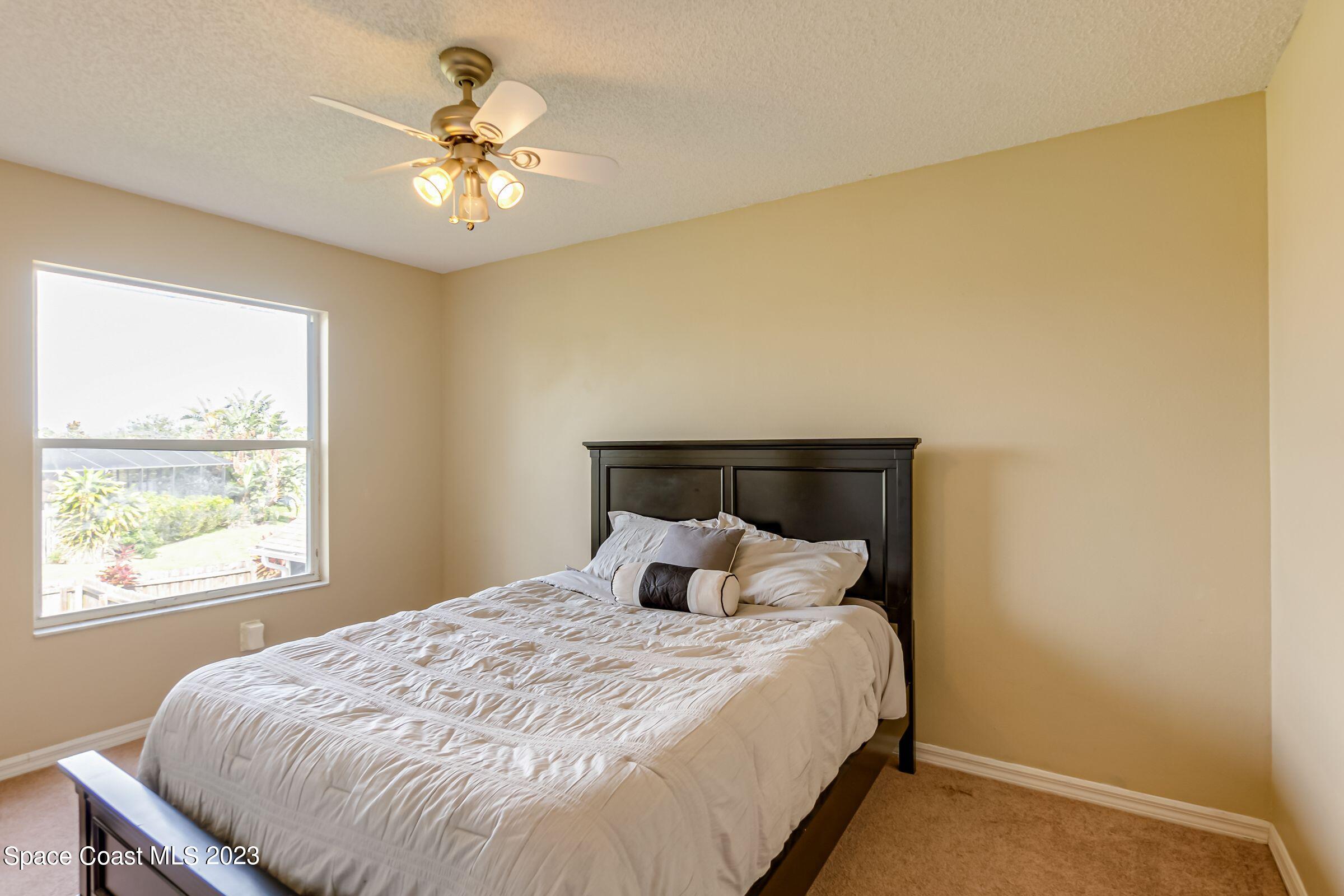 4540 Rivermist Drive Melbourne, FL 32935 - Photo 26 of 39 a bedroom with a bed and a chandelier