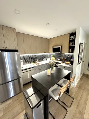 a kitchen with stainless steel appliances granite countertop a refrigerator a stove a sink a dining table and chairs