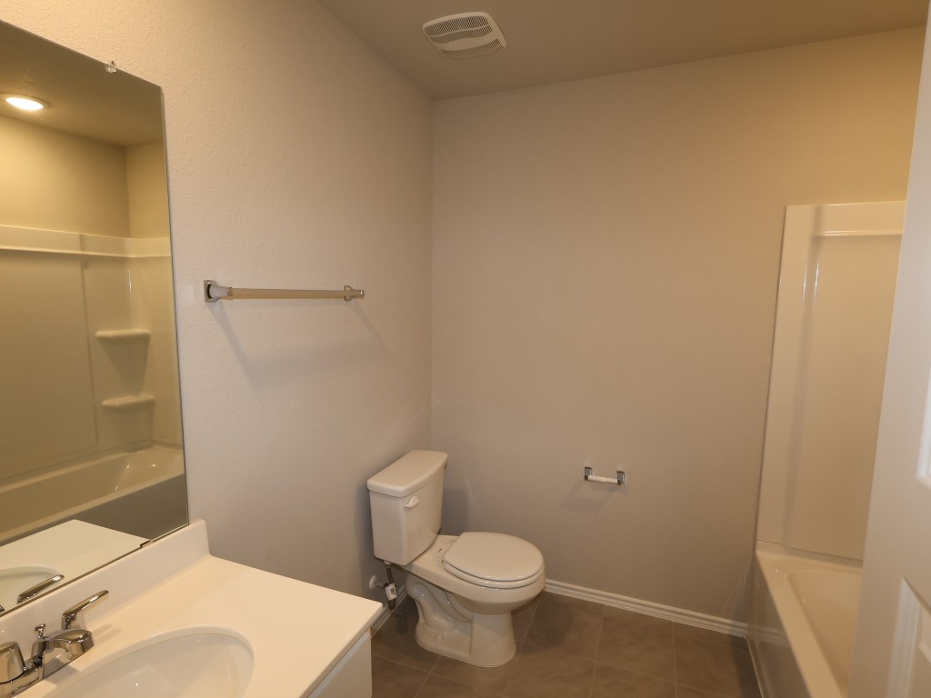 13709 Warnock Trail Manor, TX 78653 - Photo 17 of 25 a white toilet sitting next to a bathroom sink and a shower