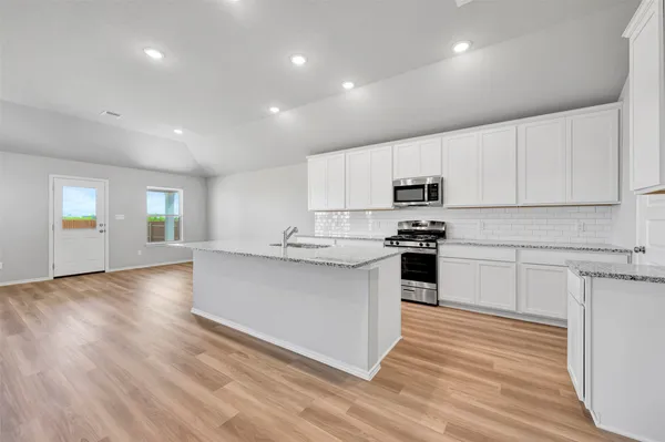 a kitchen with granite countertop white cabinets and stainless steel appliances
