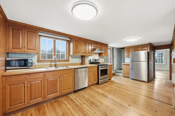 a kitchen with granite countertop a refrigerator a stove top oven and wooden floors