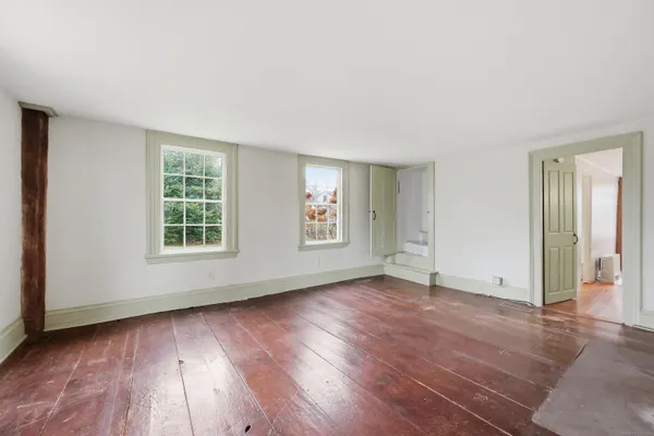 an empty room with wooden floor and windows