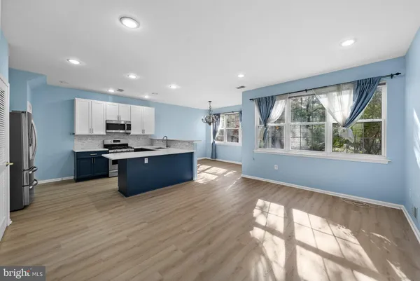 a kitchen with stainless steel appliances kitchen island granite countertop a stove a refrigerator a sink a refrigerator with wooden cabinets and wooden floor