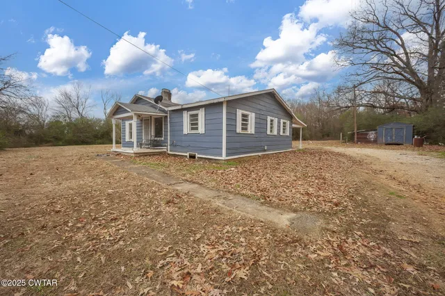 a front view of a house with a garden and trees