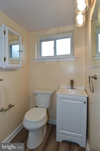 a bathroom with a toilet a sink a mirror and a window