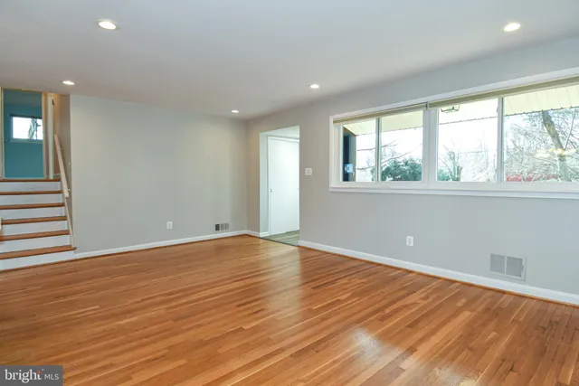 an empty room with wooden floor and windows