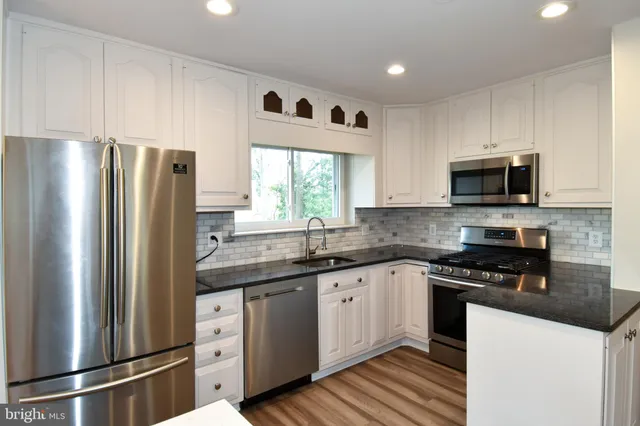 a kitchen with stainless steel appliances granite countertop a refrigerator sink and microwave