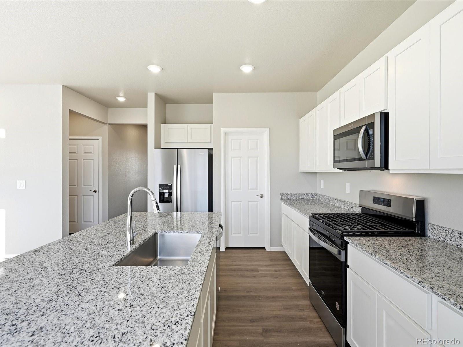 7317 West 27th St Road Greeley, CO 80634 - Photo 11 of 28 a kitchen with kitchen island granite countertop a stove top oven a sink a dining table and chairs