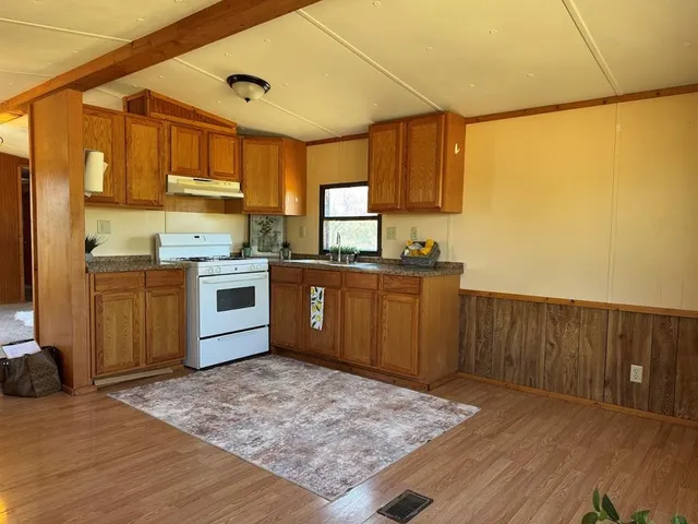 a kitchen with stainless steel appliances granite countertop a sink stove and wooden cabinets
