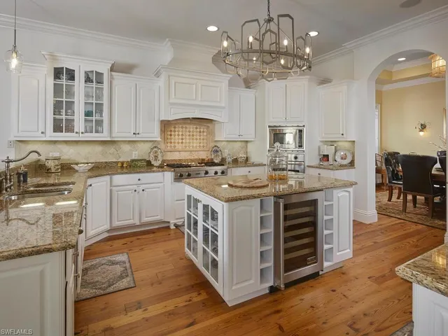 a kitchen with stainless steel appliances a white stove top oven cabinets a dining table and chairs