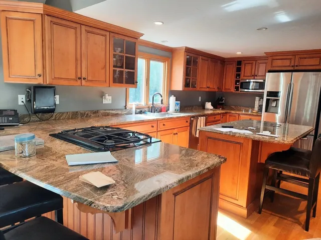 a kitchen with stainless steel appliances granite countertop a stove top oven a sink and a refrigerator