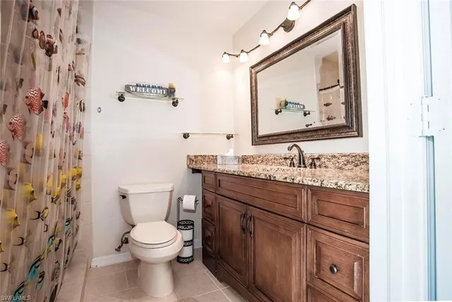 a bathroom with a granite countertop toilet a sink and mirror