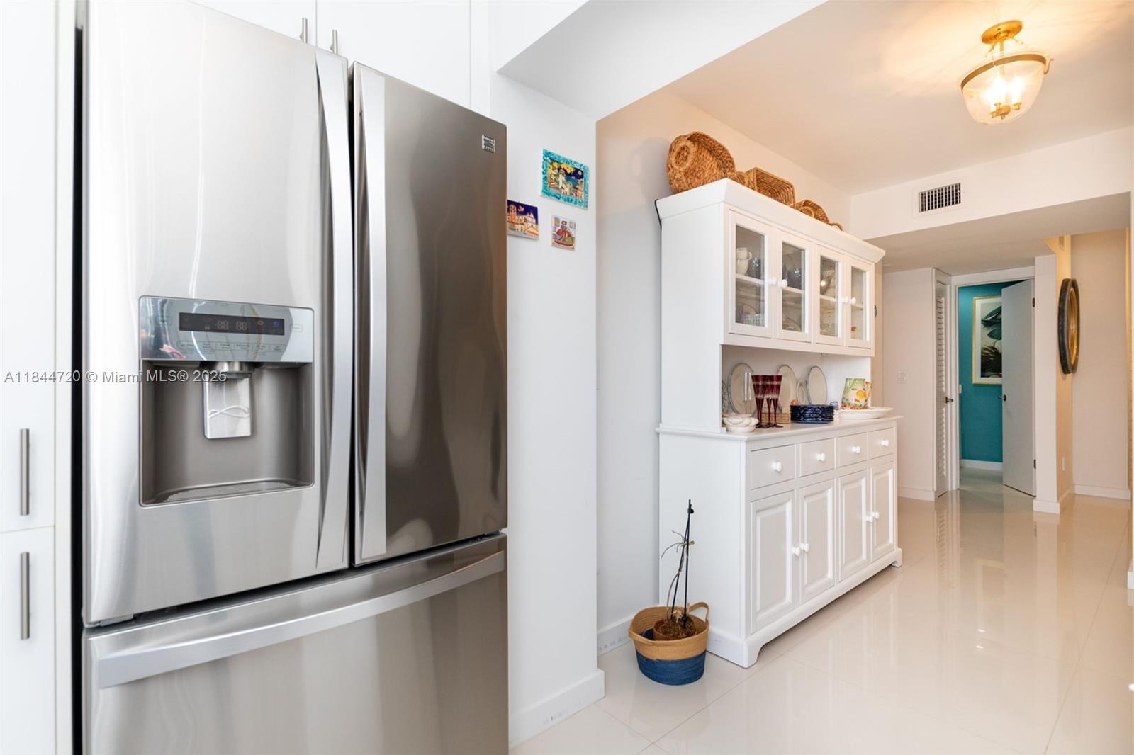 77 Crandon Boulevard, Unit 5B Key Biscayne, FL 33149 - Photo 19 of 41 a kitchen with refrigerator and cabinets