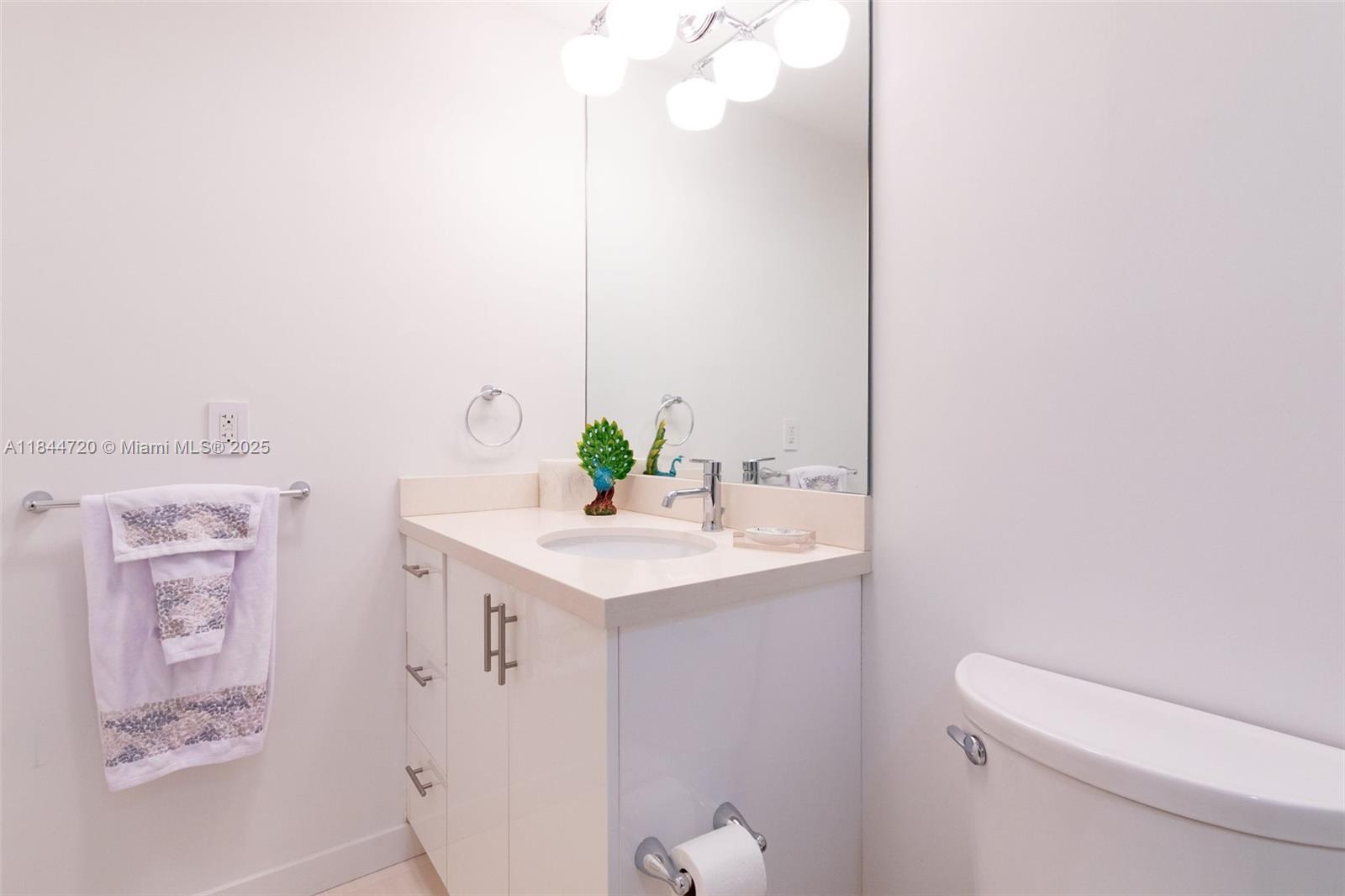 77 Crandon Boulevard, Unit 5B Key Biscayne, FL 33149 - Photo 33 of 41 a bathroom with a sink a toilet and mirror