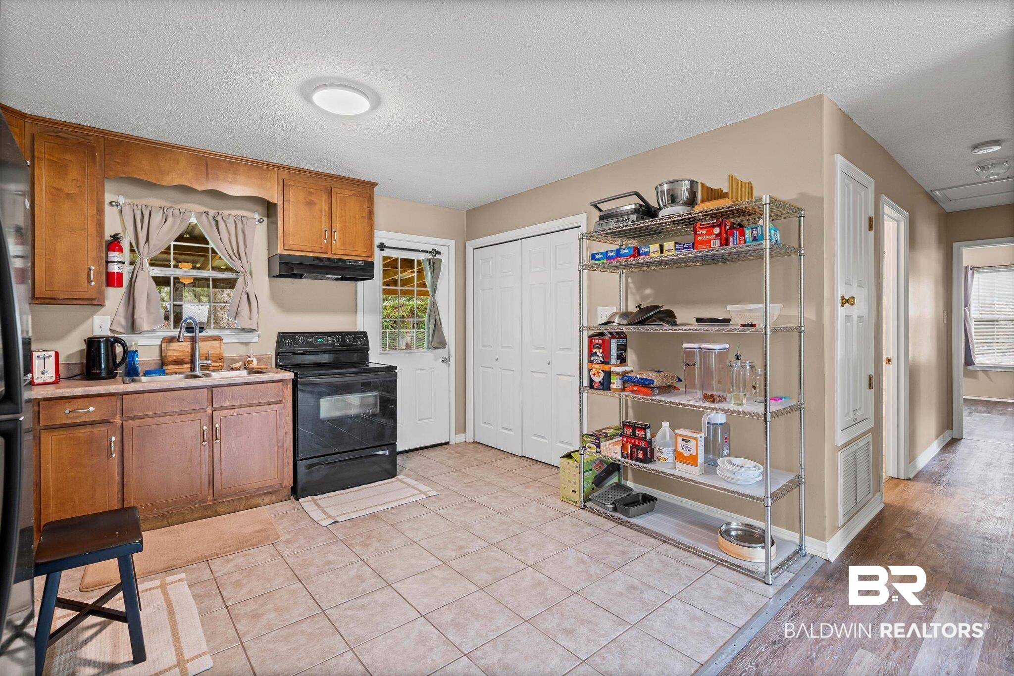14165 River Oaks Road, Unit A & B Coden, AL 36523 - Photo 5 of 35 Kitchen with brown cabinetry, black range with electric cooktop, a textured ceiling, light countertops, and light tile patterned flooring
