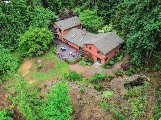 an aerial view of a house with a yard and trees all around