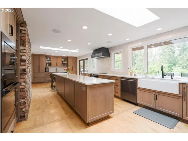 a large kitchen with stainless steel appliances granite countertop a large counter top a stove and a sink