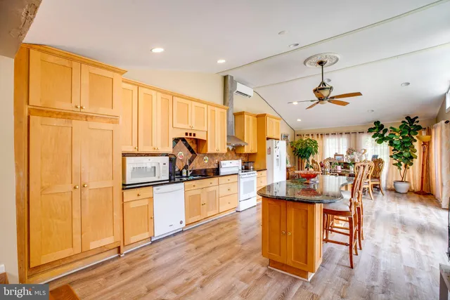 a kitchen with a refrigerator a oven a stove a dining table and chairs with wooden floor