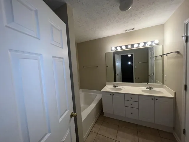 a spacious bathroom with a double vanity sink a mirror and a bathtub