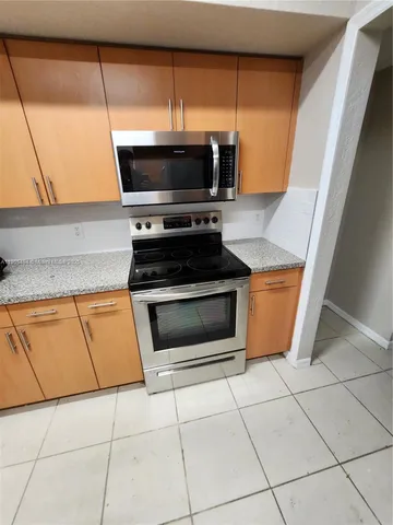 a kitchen with granite countertop a stove a microwave and a sink