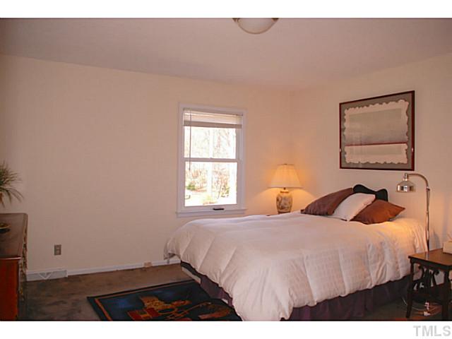 1507 Stonehurst Road Raleigh, NC 27607 - Photo 10 of 23 a bedroom with a bed and a lamp on dresser