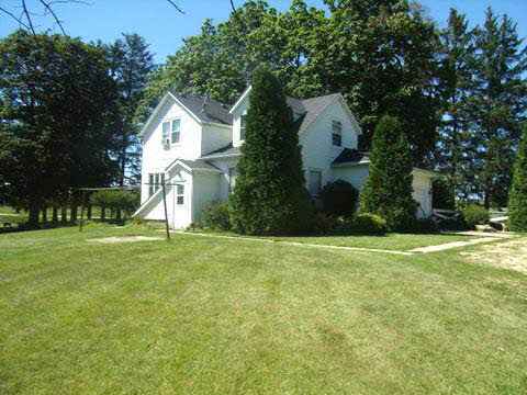 a front view of a house with a yard and trees
