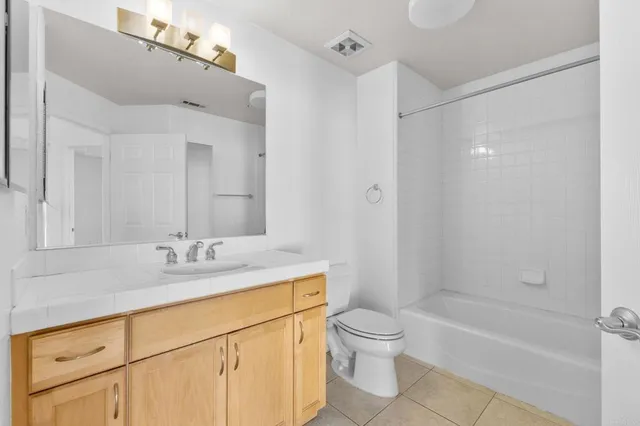 a bathroom with a granite countertop sink a toilet a mirror and shower