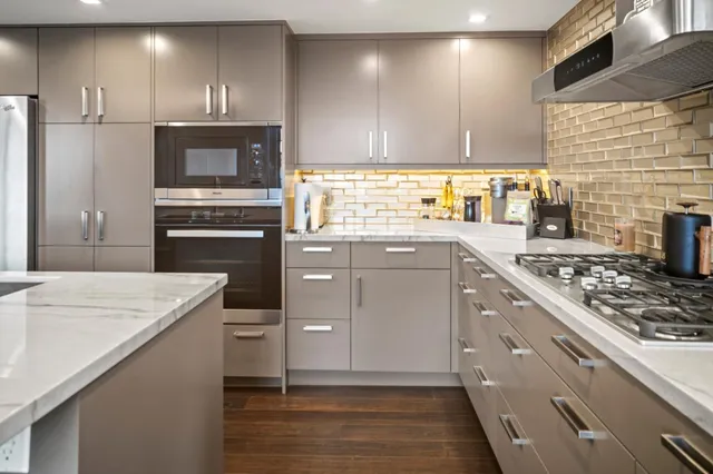 a kitchen with stainless steel appliances a refrigerator a sink dishwasher a stove and a dining table with wooden floor