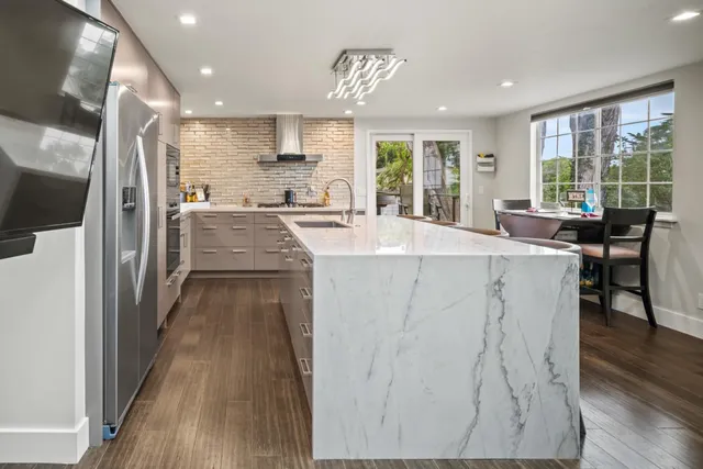 a sink with a granite countertop white cabinets and a window