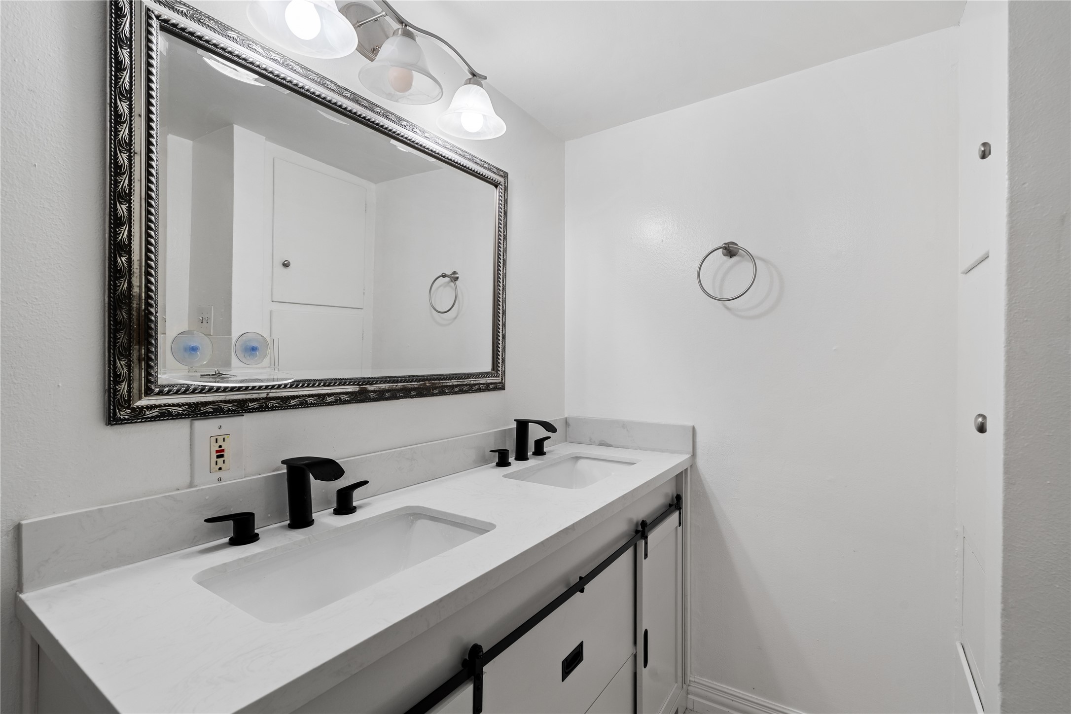 6303 Crab Orchard Road, Unit 3 Houston, TX 77057 - Photo 21 of 30 This en-suite is a masterclass in modern design. It features a stunning double vanity with a crisp quartz-style top and dual integrated sinks. The matte black designer faucets provide a bold, contemporary contrast, while the oversized silver-leaf framed mirror and triple-light sconce ensure you always have the perfect glow.