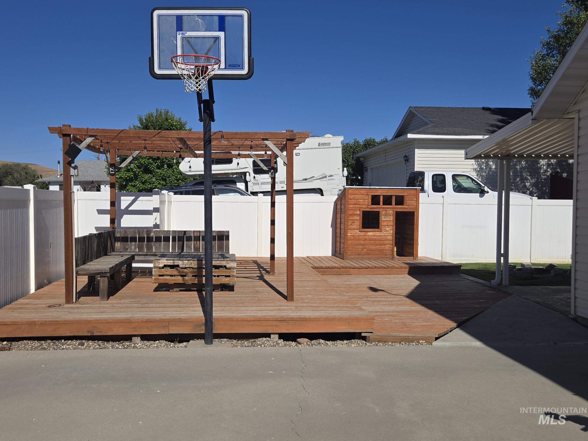 2480 West 9th Street Weiser, ID 83672 - Photo 17 of 17 Expansive wood-finish deck featuring a pergola structure, built-in bench seating, and a basketball hoop